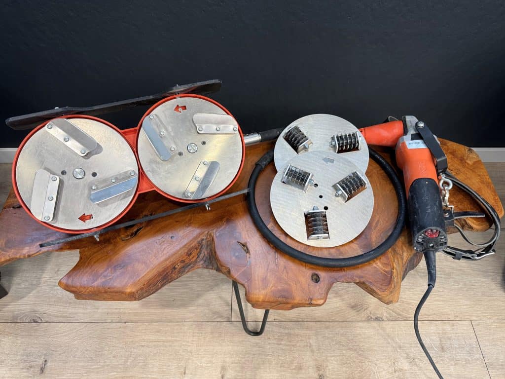 Eine orange schwarz farbige Universalschleifmaschine mit Schabeteller und Perforierteller auf einem Holztisch abgelegt zum Mieten bei Take my Tool